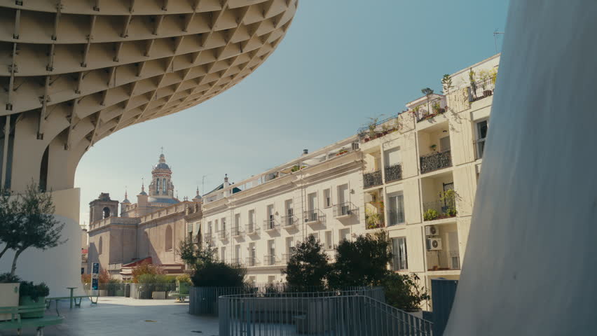 View of Metropol Parasol in Seville, Spain with surrounding historic buildings and city life, showcasing a blend of modern architecture and traditional urban design on a sunny day in spring.