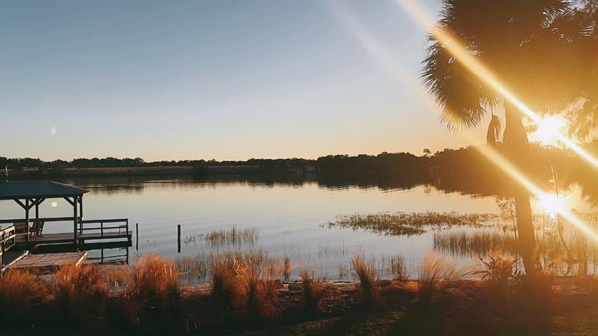 covered lakeside dock with wooden walkway glowing in warm sunset light over calm water