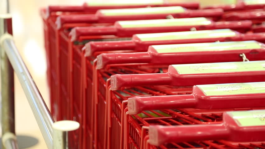 Close up of red shopping cart handles lined up at the entrance of a large mart in South Korea. Concept of retail shopping preparation, consumer service, and organized mart environment in Korea.