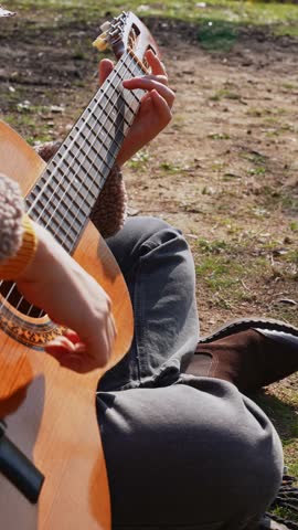 Close up of hands playing string guitar outdoors in autumn forest. Concept of sound therapy, mental health and wellness rituals. Calmness tranquility audio-sensory practices. Aura farming energy