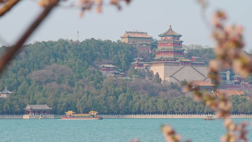 Beautiful panoramic view of ancient Chinese architecture at Summer Palace with traditional boat on the water and historic pavilion on the hill during spring season in Beijing