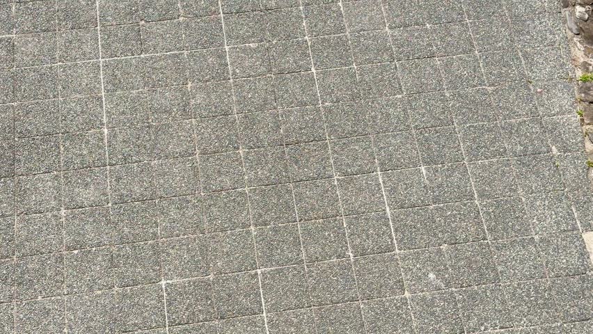 Cyclist in helmet riding bike over textured stone path outdoors.