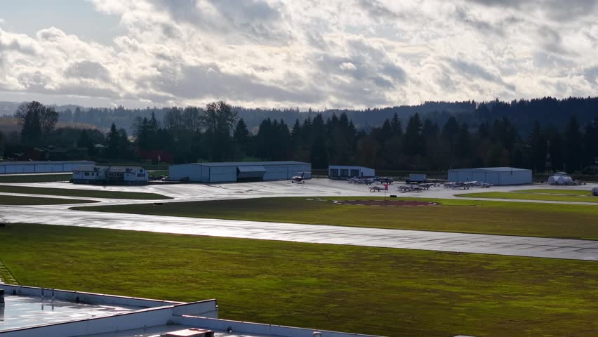 Small airplane going into hanger lush grass and cloudy sky