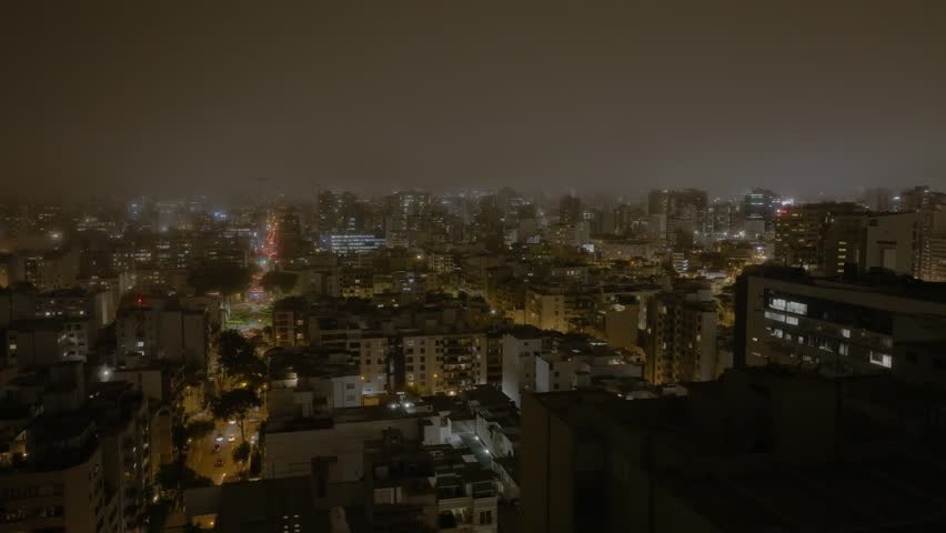 Night aerial view of Miraflores district in Lima, Peru, showcasing illuminated buildings, coastal lights, and vibrant urban life along the Pacific Ocean. Modern cityscape at night.