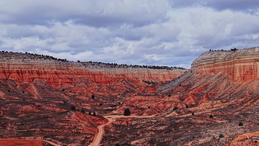 Travelers walk through the rocky terrain of Spain. Bright orange red rocks and clear skies create a unique landscape. People enjoy the view while learning about nature and geography.