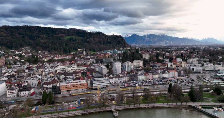 Aerial view of Bregenz city nestled between the lake and mountain, with a dramatic sky casting shadows over the water, Bregenz, Austria.