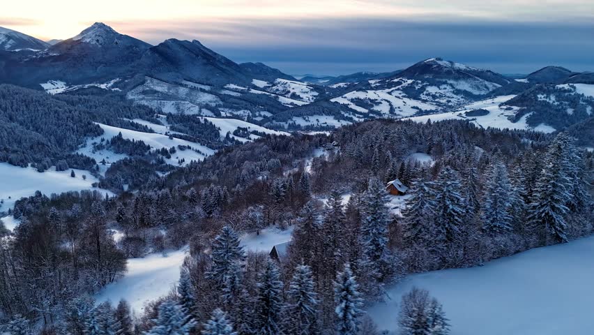 Aerial hyperlapse of dramatic clouds moving over winter mountain peaks and snowy forest