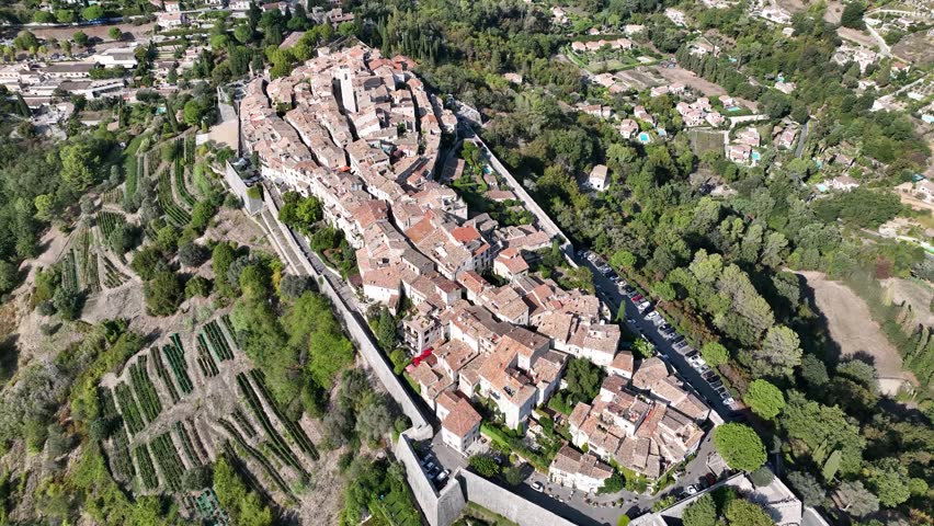 Aerial view of Saint-Paul-de-Vence village with its medieval architecture and terracotta rooftops nestled amid lush greenery, Saint-Paul-de-Vence, France.