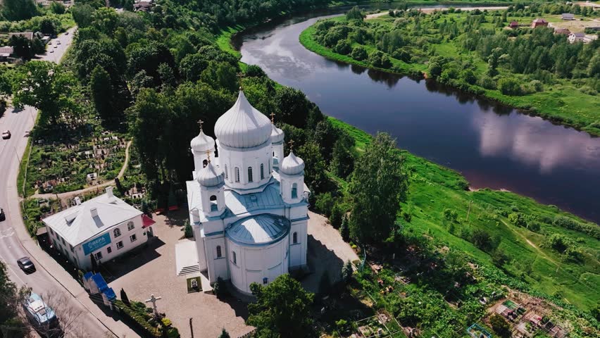 A large Orthodox church stands on the high bank of the river. Filming is conducted from the air