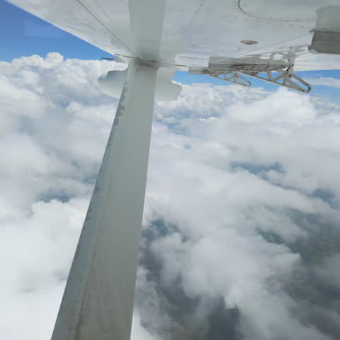 View of airplane wing during flight through bright white clouds with peaceful sky atmosphere