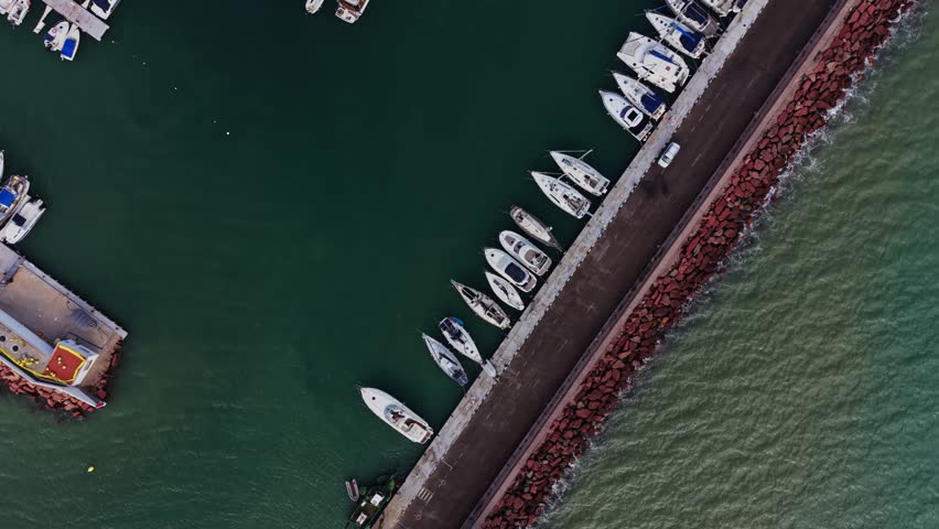 Boats are lined up at a marina in Spain. The marina has many small vessels and is surrounded by calm water. This scene captures a busy area for boating and leisure activities.