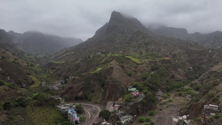 Aerial drone volcanic ridges and steep mountain trails in Santo Antao, Cape Verde. Dramatic rocky peaks covered in fog and low clouds in a remote highland landscape