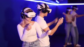 Young couple in VR glasses playing video game against another couple. Friends are enthusiastically playing a game in a virtual reality headset and using joysticks - Powered by Shutterstock - Get 15% off with code: PIKWIZARD15