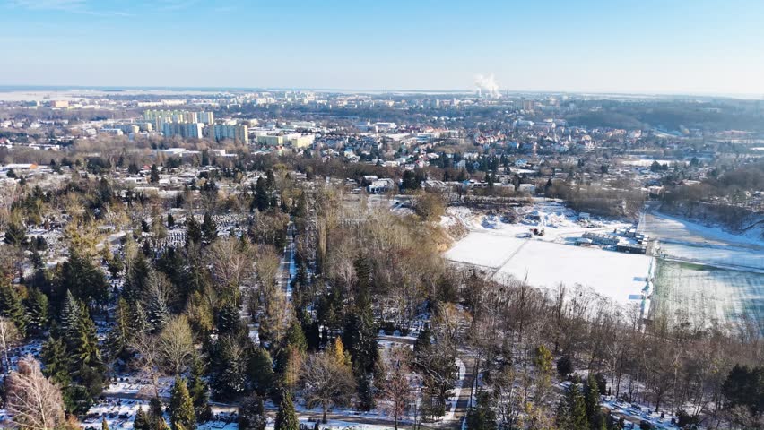Aerial fly over view of Żwirowa Street Municipal Cemetery with Piaski and Manhatan residential areas in the background. Gorzów Wielkopolski in winter. Poland