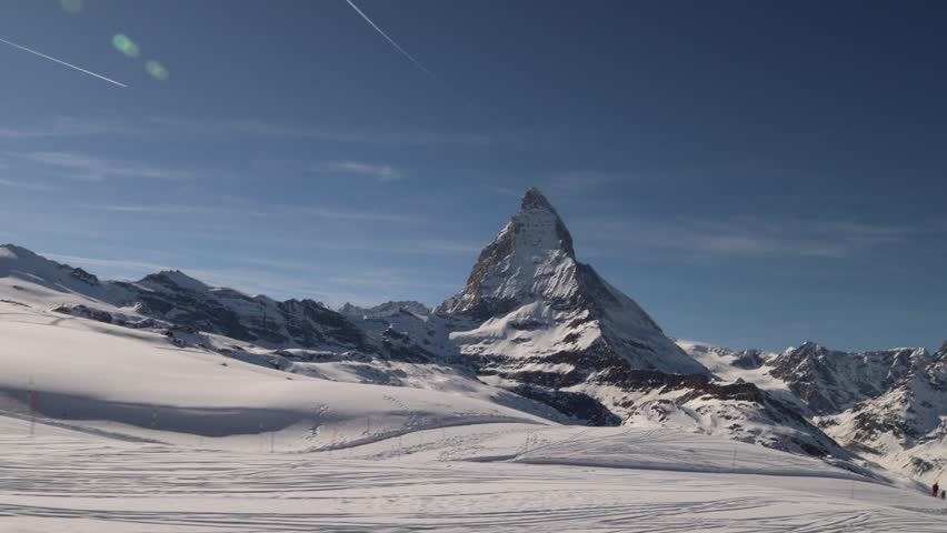 People skiing in Zermatt ski resort below Matterhorn, establishing wide view.