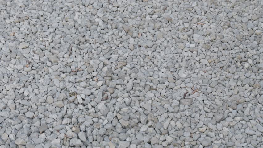 White gravel pebble surface filmed from above. Minimal stone texture background with natural rough pattern.
