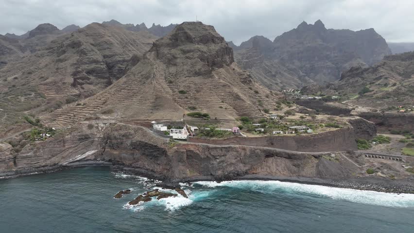 Aerial drone view of Cruzinha village coastline in Santo Antao, Cape Verde. Dramatic volcanic mountains meet the Atlantic Ocean with rugged cliffs, terraced slopes and crashing waves