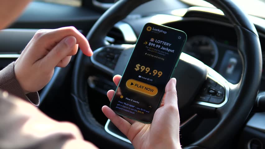 Man playing online slots on smartphone in car. Close up of hands tapping spin button in mobile gambling app interface. High quality POV shot of digital entertainment, casual gaming and mobile betting