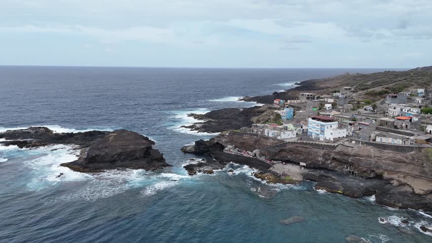 Aerial drone shot of Cruzinha fishing village on the rocky coast of Santo Antao, Cape Verde. Panoramic view of traditional houses by the Atlantic Ocean with crashing waves and volcanic rocks
