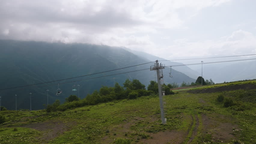 Drone side View of Chairlift at Veduchi Mountain Resort, Green Кавказ Hills and Light Rays Breaking Through Clouds, Chechnya 4K