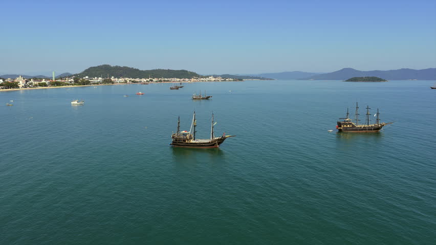 Pirate style tour ships in Cachoeira do Bom Jesus and Canasvieiras Florianópolis Santa Catarina Brazil on Baía Norte with calm sea and coastal skyline backed by Serra do Mar, static aerial shot