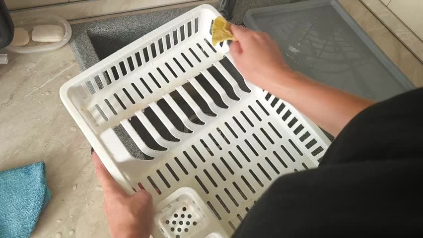 Top view - a woman wipes a plastic dish dryer with a sponge on a kitchen countertop, cleaning, hygiene, cleanliness, home life.