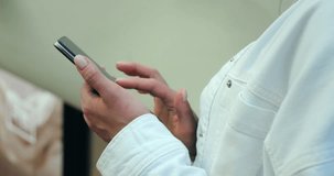 Closeup hands holding smartphone tapping screen. Casual person in white jacket interacting with touchscreen, composing message, scrolling social feed, checking notification, soft indoor lighting, - Powered by Shutterstock - Get 15% off with code: PIKWIZARD15