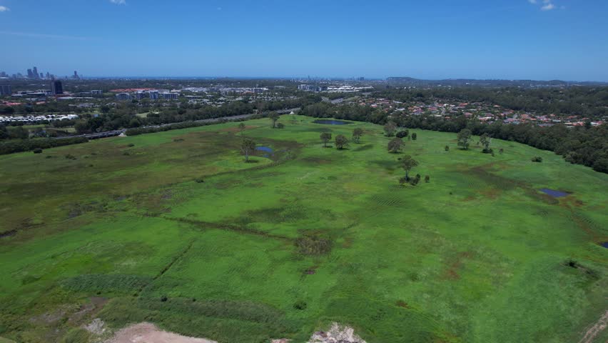 Green Fields With Suburbs In Mudgeeraba, Gold Coast, Queensland, Australia - Drone Shot