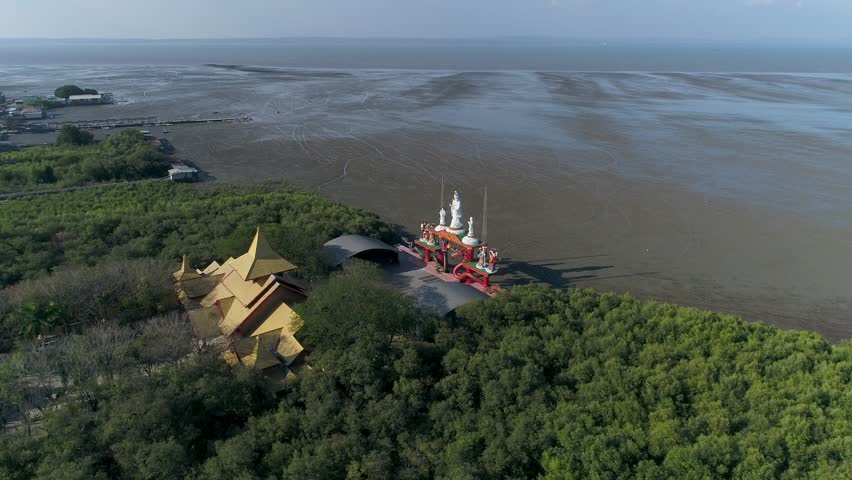 Cinematic drone footage showcasing the unique architecture of Sanggar Agung Temple, a spiritual Tridharma site nestled within the lush greenery of Kenjeran Park and the East Java shoreline
