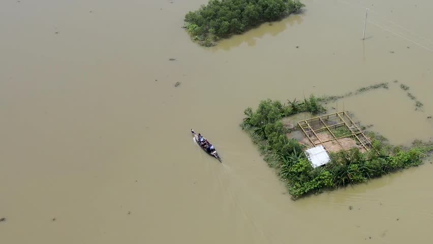 Aerial view of a boat navigating through a flooded water at village in sylhet, bangladesh. people leaving village