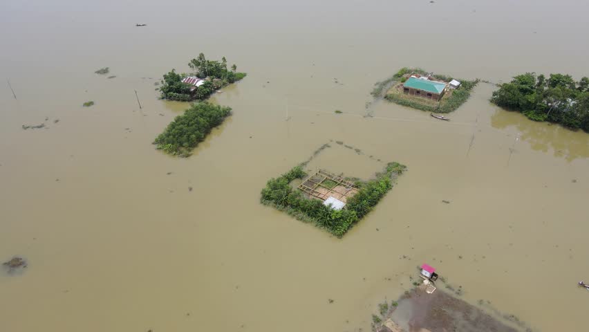 Aerial view of flooded village with a boat crossing through floodwater in Bangladesh