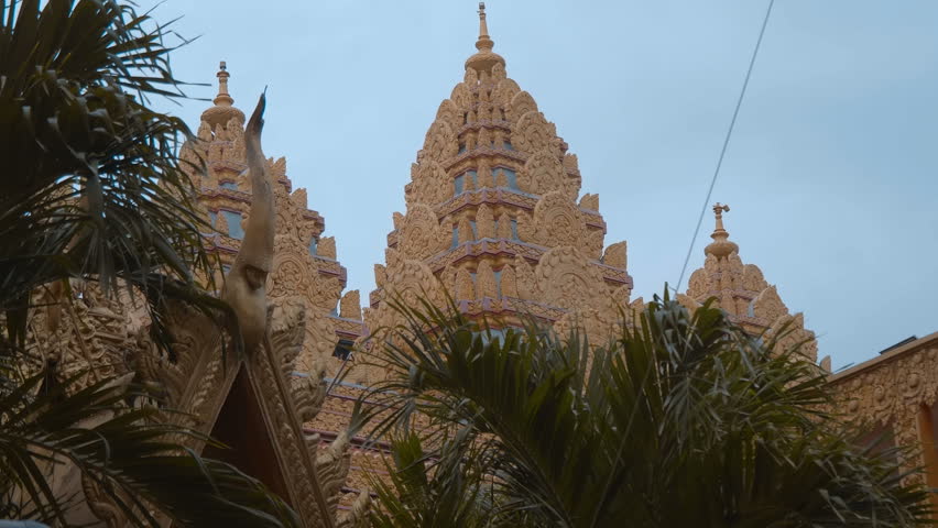 Picturesque ornate golden dome shape towers of the beautiful Asian style Chua Chantarangsay Temple in Saigon raiding above the palm trees. Ho Chi Minh City, Vietnam