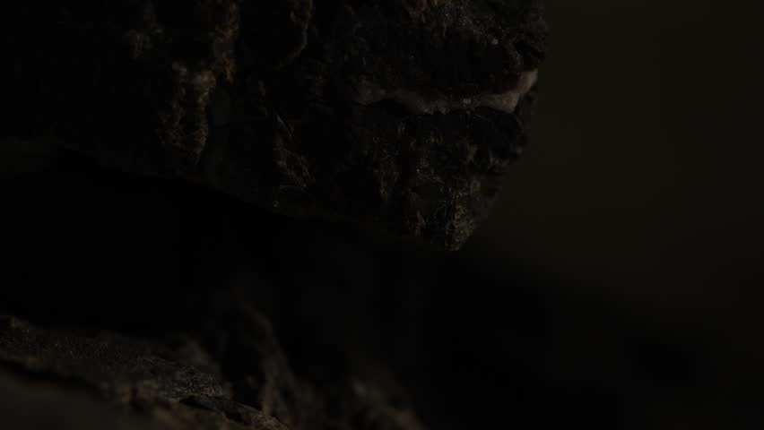 Close-up dark rock layers with rough texture and deep shadows