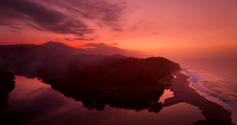 Vivid warm hues from sunset over Tayrona National Park river and coast, drone