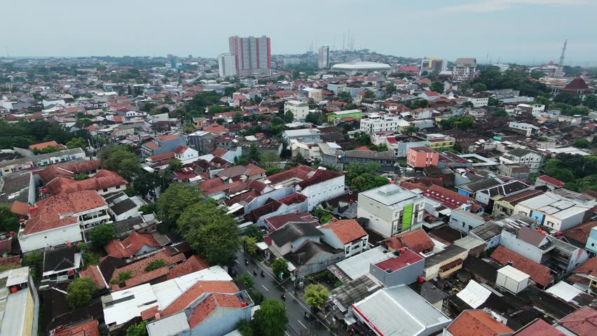 A high angle drone shot capturing the vast sprawl of houses and buildings in a busy metropolitan area with a hazy sky in Semarang, Indonesia.