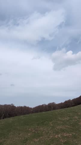 Steep mountain slope with dark rocks and patches of snow, immersed in a cold and cloudy atmosphere that recalls the seasonal transition between winter and spring