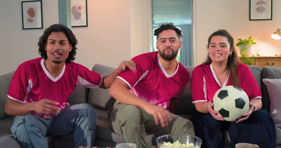 Big match fueling friends in red jerseys grabbing popcorn with ball reacting then relaxing on sofa. Fans, camaraderie, celebration, relaxation, sportswear, casual, entertainment