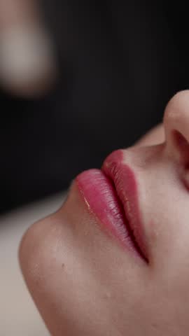 Closeup slow motion application of lip tint after permanent on woman lips in beauty studio.