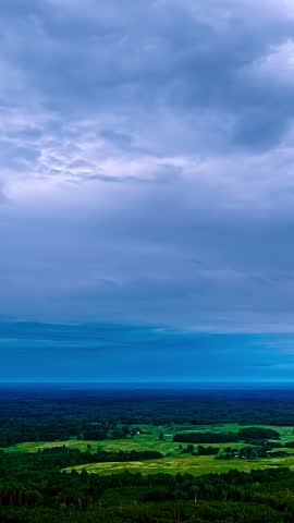 Dramatic storm clouds above expansive green countryside and farmland landscape