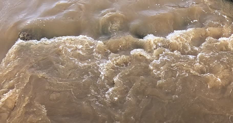 Turbulent, muddy brown water with white foam in Vantaanjoki river, Helsinki, Finland, Europe.