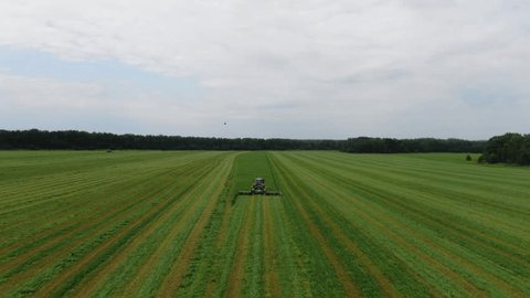Drone Following Tractor Mowing Grass on Field