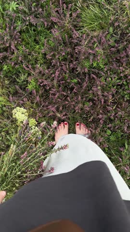 An overhead view of barefoot women standing among wildflowers, holding a bouquet of wildflowers, their clothes fluttering in the wind. Oneness with nature, rest, relaxation, a natural and summery scene