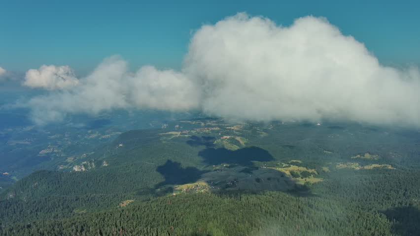 Aerial view on mountains, hills and meadow, village under clouds in Tara national park, Serbia, 4k