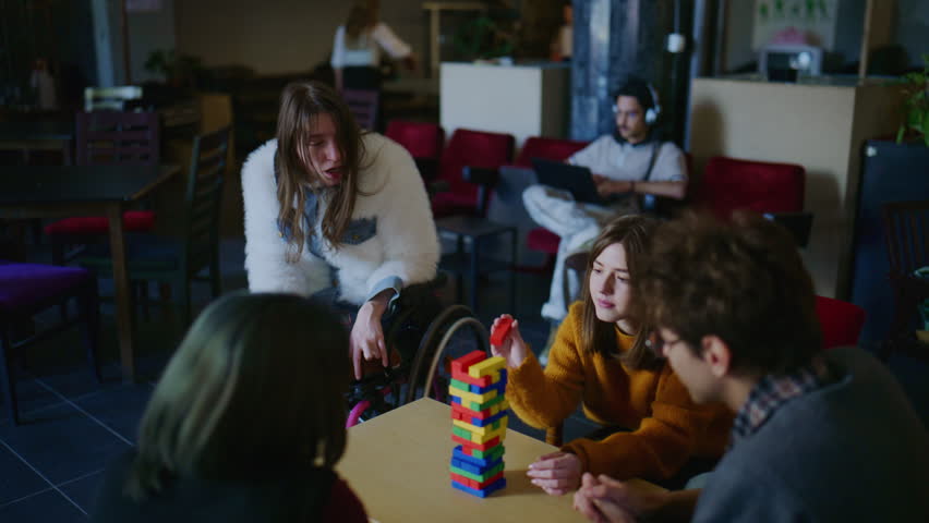 Diverse university students play a game, showcasing friendship and inclusive campus life. This group of young people enjoys a social activity in a modern, common area.