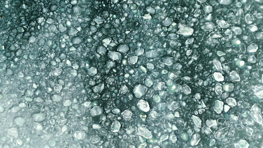 Aerial view of frozen sea with floating ice floes and slush.