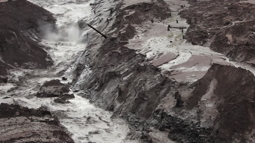 Destructive mudflow torrent rushing through a gorge, causing severe soil erosion