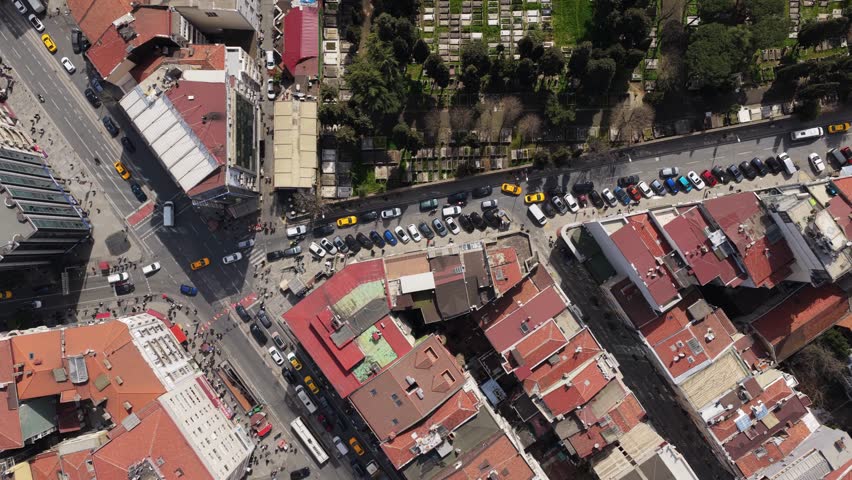 Top down aerial over bustling street and intersection in dense urban neighborhood of Istanbul, Turkey, daily life with cars, people, buildings