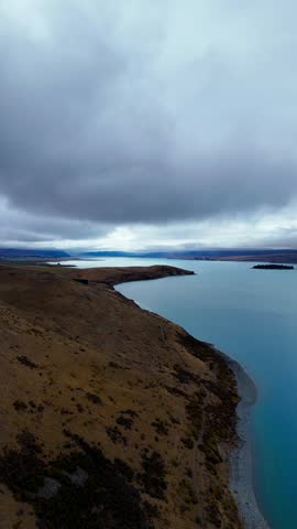 Drone view of the landscape along Lake Tekapo with a walking path along the mountainside.