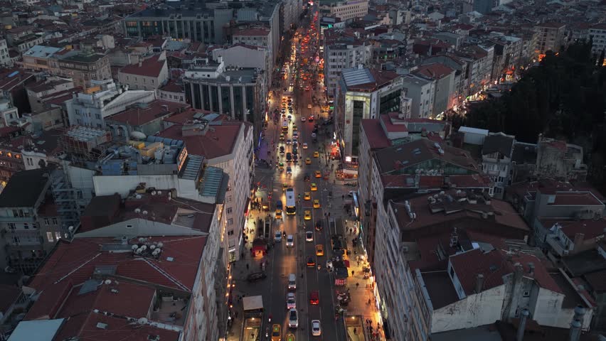 Busy Istiklal Avenue at twilight with glowing streetlights, pedestrians and vehicles moving through Beyoglu