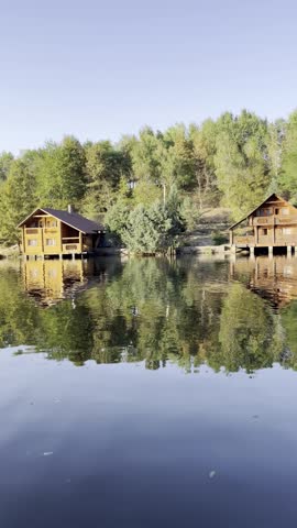 wooden cabins on lake in forest landscape
